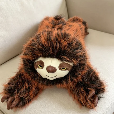 Nappy the sloth plush relaxing spread out on a cream armchair, showing its full arm span at home